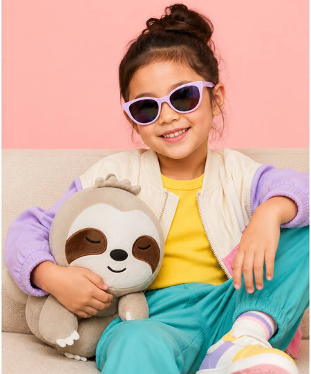 Child holding a sloth stuffed animal while relaxing on a sofa