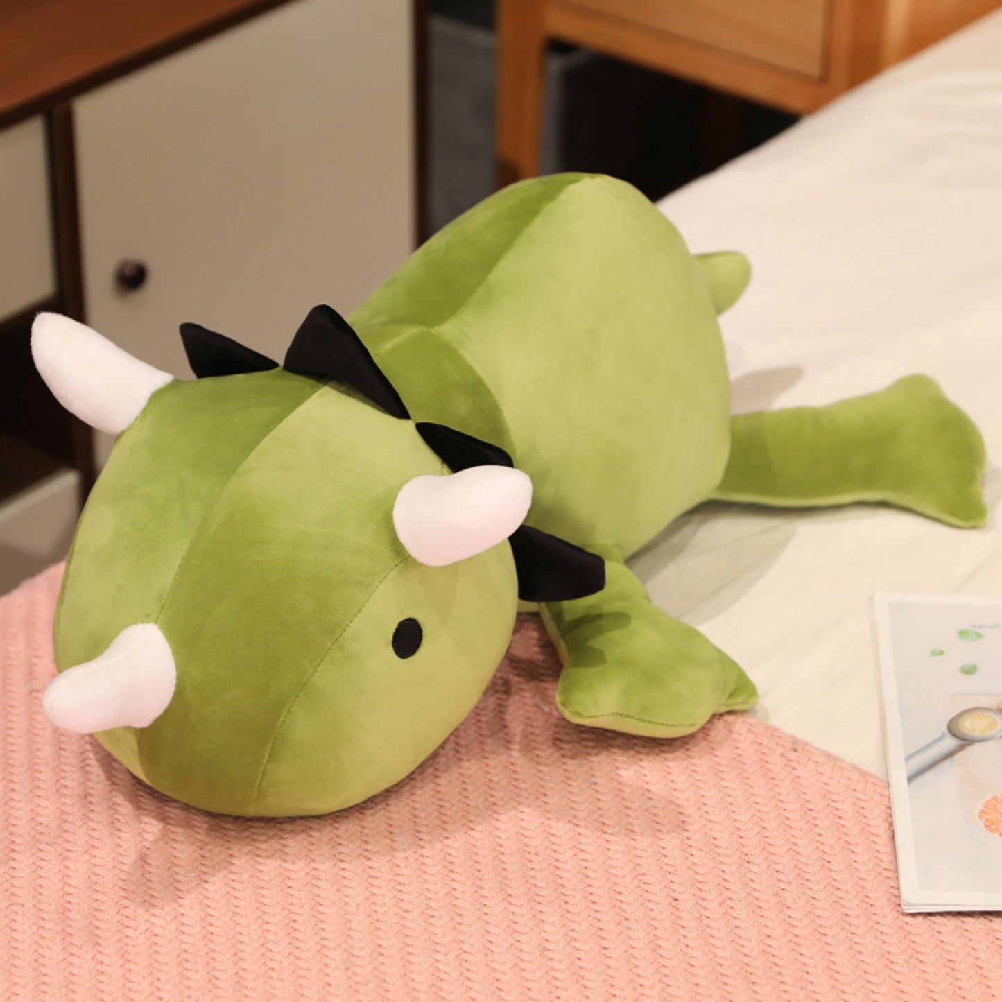 SQEQE giant triceratops stuffed animal displayed on a bed in a side product view