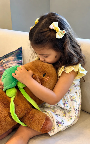 Brown capybara stuffed animal with a turtle plush displayed on top