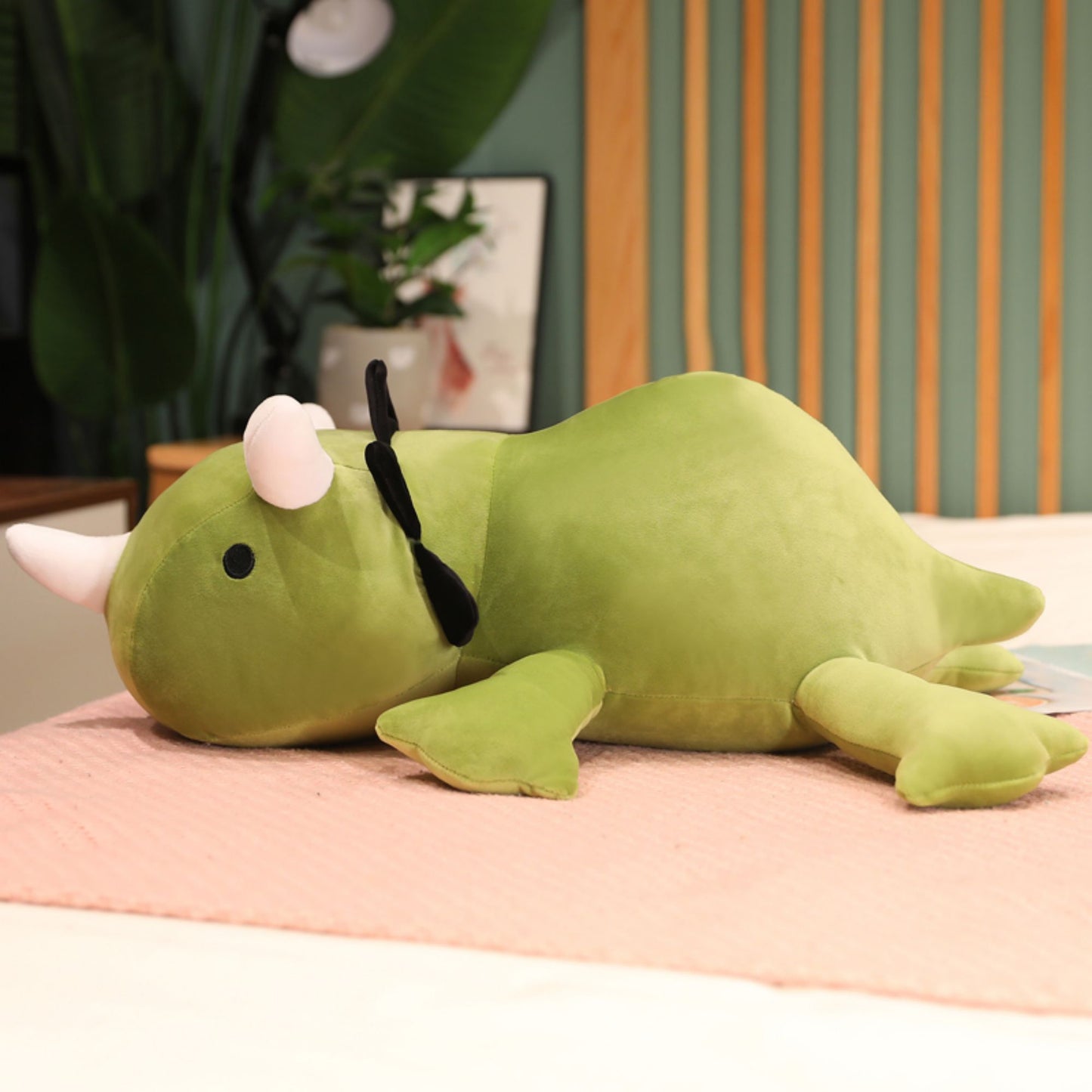 SQEQE giant triceratops stuffed animal shown in a second long body view on a bed