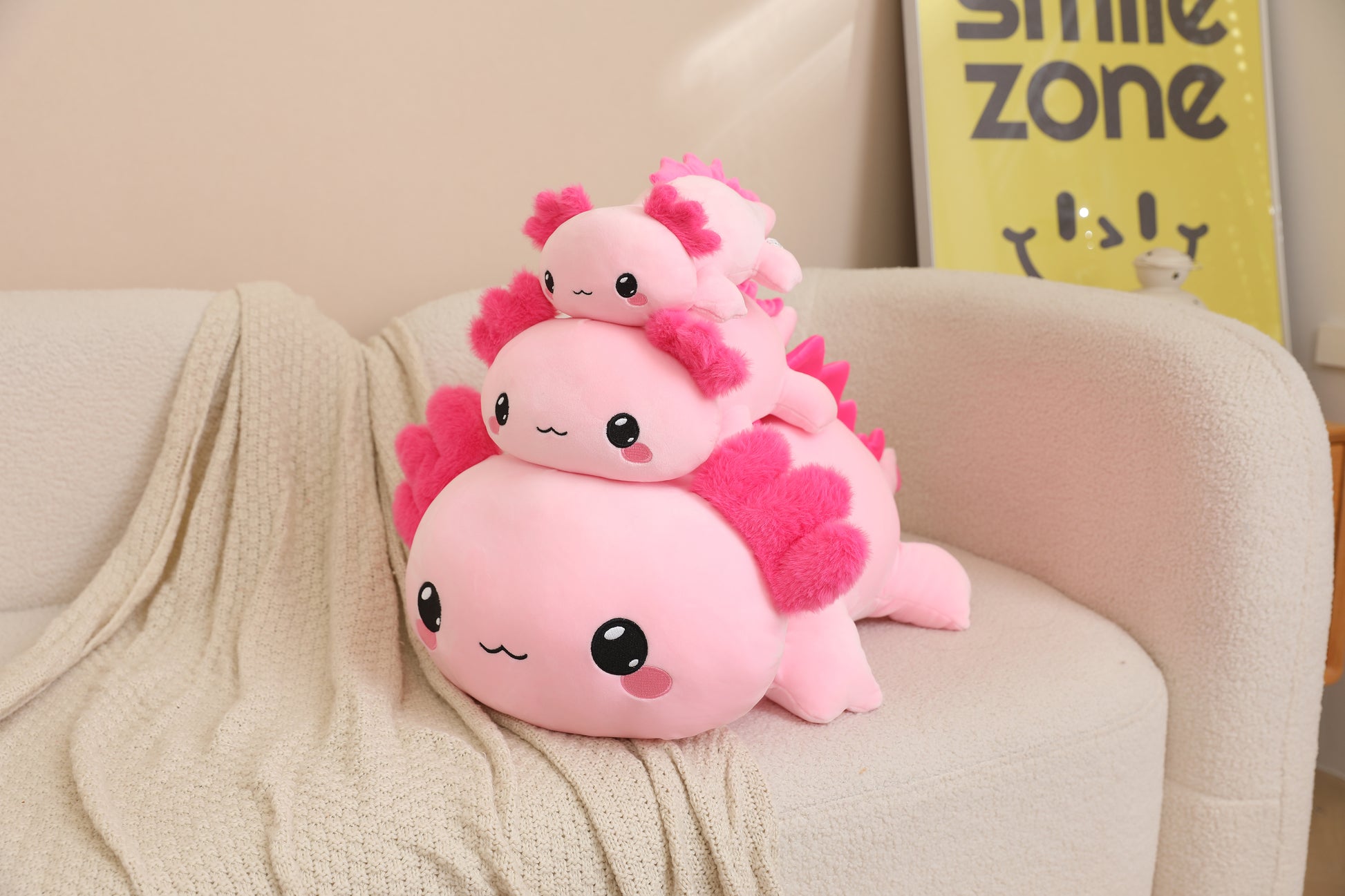 SQEQE weighted axolotl stuffed animal stacked in multiple sizes on a sofa