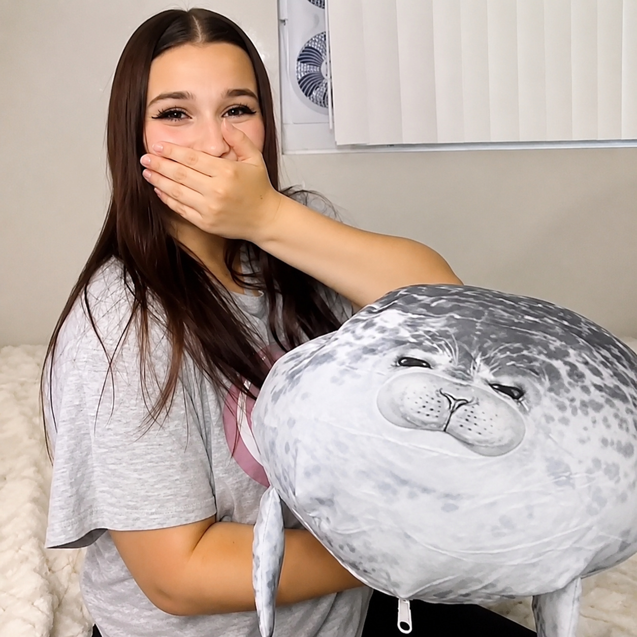 SQEQE seal stuffed animal with babies hugged by a child with the baby seals arranged nearby