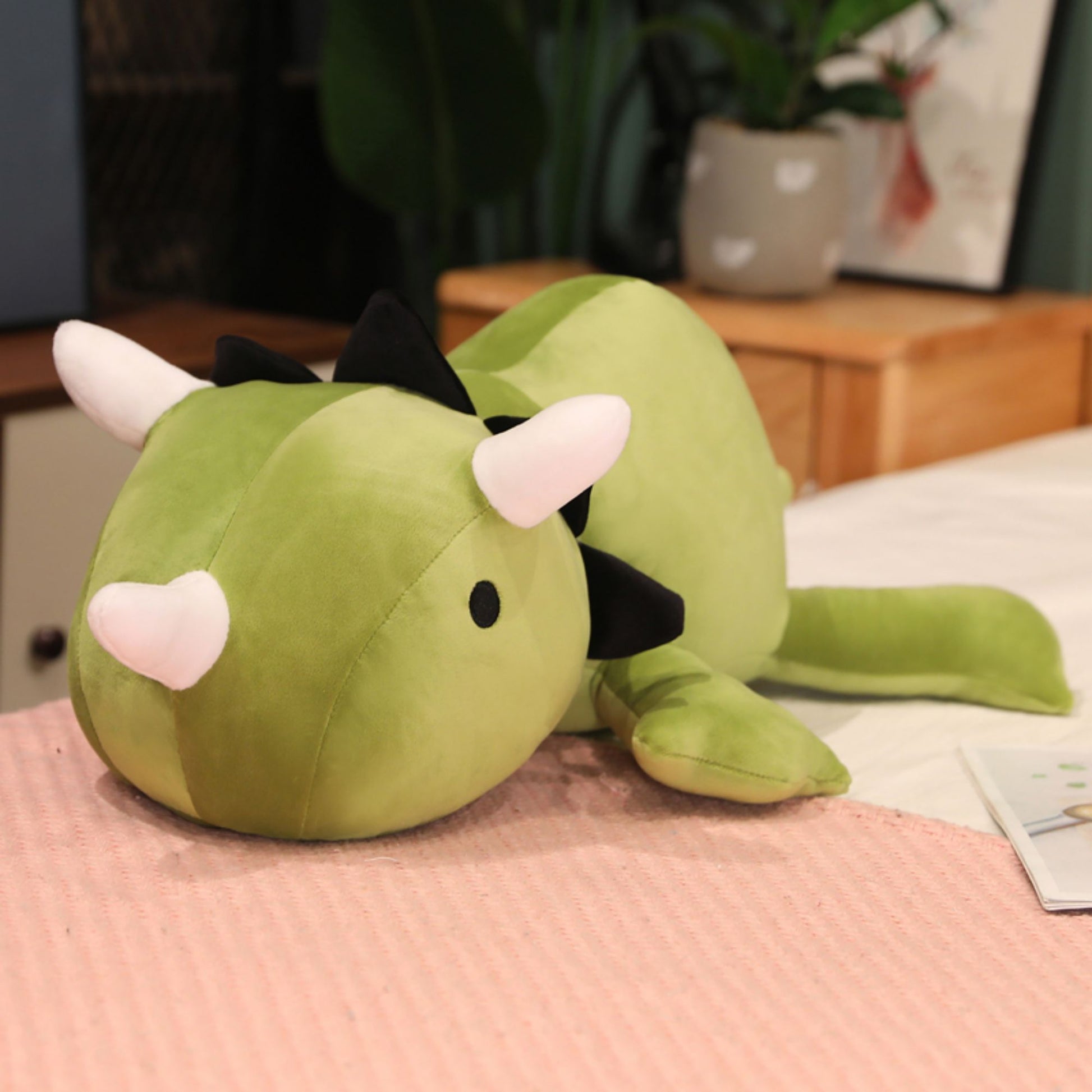 SQEQE giant triceratops stuffed animal used as a soft desk companion beside a laptop
